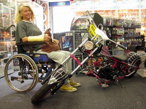 Sylvia in wheelchair, looks doubtful to a Chinese mini Harley