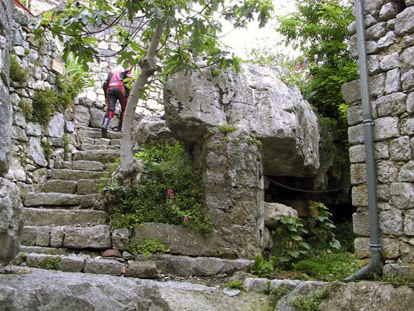 Natuurstenen grijze trap in dorpje, motorrijder in rood leren pak loopt naar boven