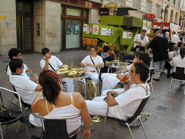Jonge mensen aan terrastafel, muziekinstrumenten op tafel, allemaal in het wit gekleed