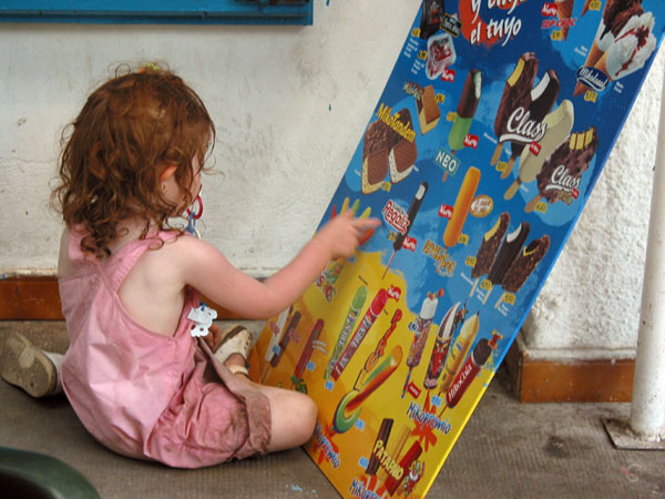 Klein meisje met rode haren op haar knietjes voor een poster met ijs