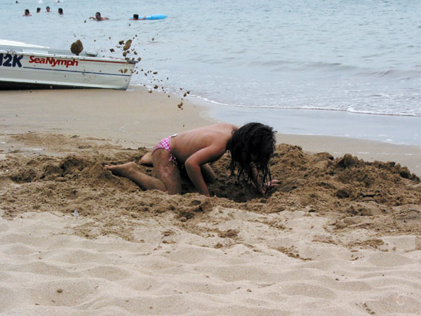 Klein meisje graaft enorme kuil op het strand