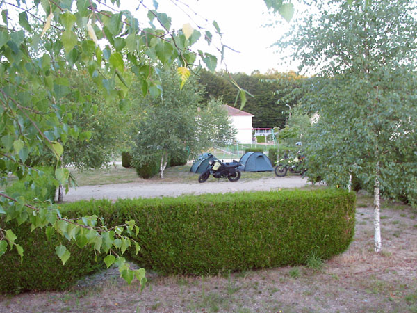 De motoren en twee groene tentjes op een plekje tussen ligusterhagen; camping verder leeg