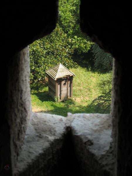 Te zien door opening in muur: houten wc huisje
