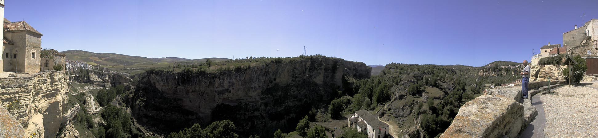 Witte loodrechte rots aan de kant van het stadje; loodrechte grijze rots aan de overkant, bomen in de kloof
