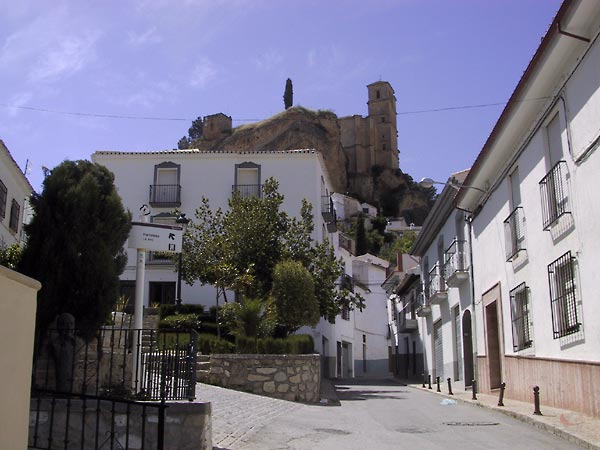 Straat met witte huizen en hoog daarboven een kasteel