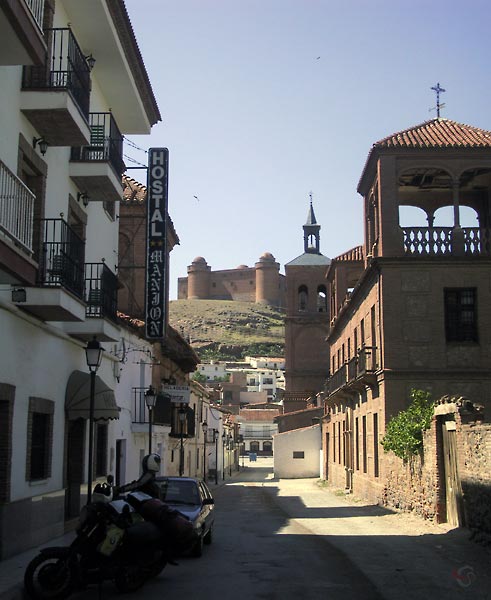 Straat met vervallen kerk, Hostal Manjon, en zicht op de heuvel met kasteel