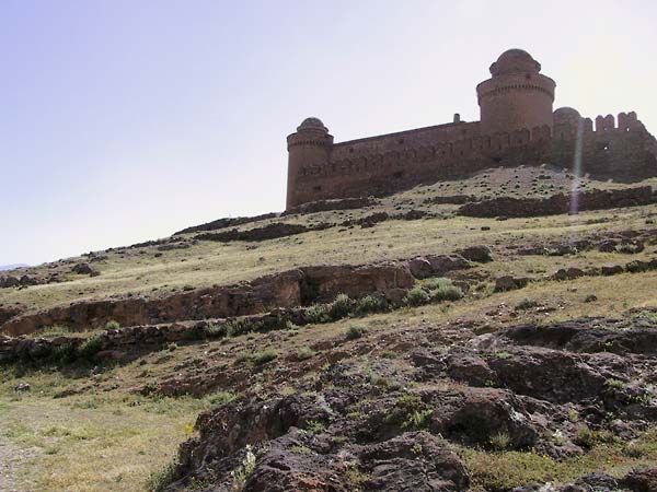 Het castillo van onderen: muur met kantelen en twee stoeren ronde torens in baksteen