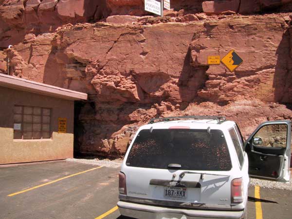 Auto tegen rotswand onder bordje met waarschuwing