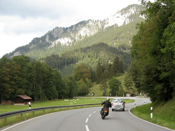 Motorcycle rider behind a car on a beautiful road