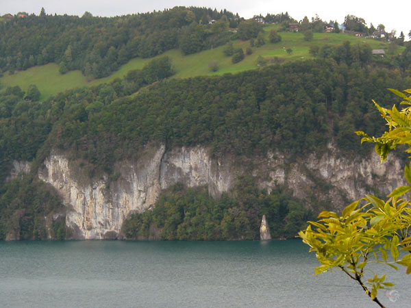 Almen (bergweiden) bovenop de rotsen aan de overkant van het meer, beeld aan de voet ervan