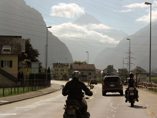 Wat huizen, twee motorrijders, bergen in de verte
