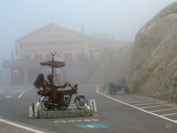 Door de mist: berghotel restaurant Grimselblick; standbeeld van motorrijders op motor