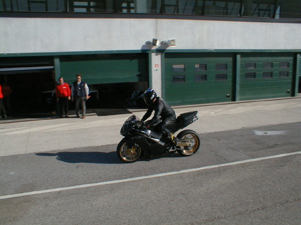 Motorcyclist in black on the SB8K; two people watching