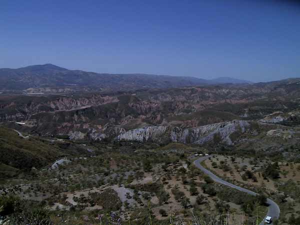 Zicht van hoog af op Alpujarras beneden: rode en grijze rotsen en groene begroeiing