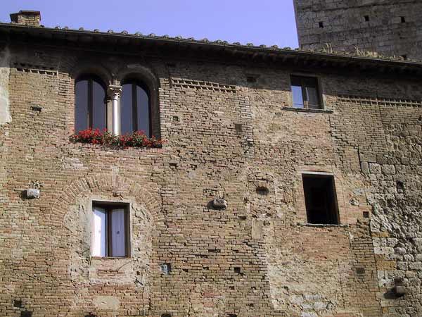 Bakstenen gevel met verschillende soorten ramen, waarin oude structuren te zien zijn