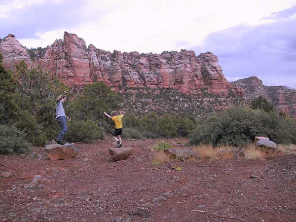 Wouter en Pieter in rood rotslandschap, springend op rotsblokken