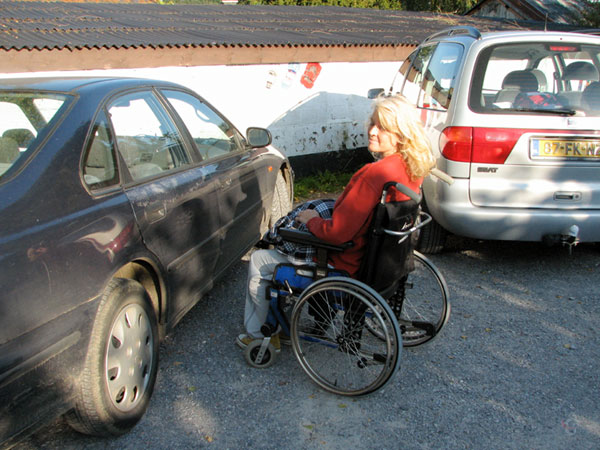Sylvia in  the wheelchair next to the car