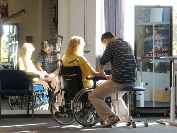 Sylvia in a wheelchair, fysiotherapist on stool
