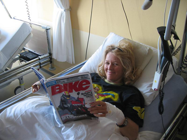Sylvia in a hospital bed, with Bike Magazine