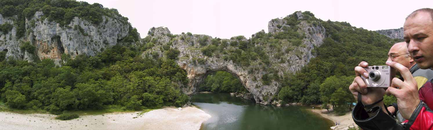 A natural bridge in grey stone, over a river