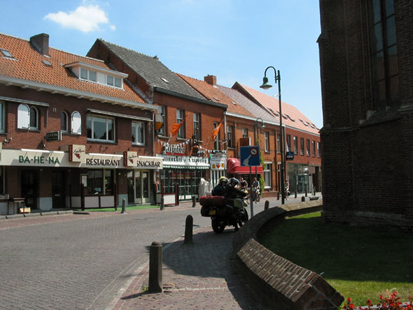 Sylvia en Pieter op de motor in straat met Jupiler-café en snackbar