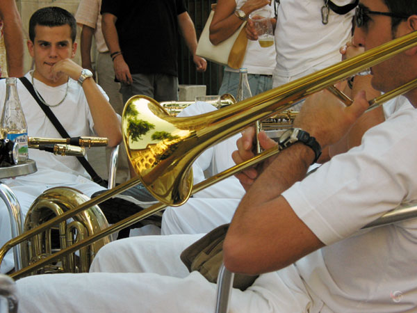 Jongen met trombone aan de mond op terrasje