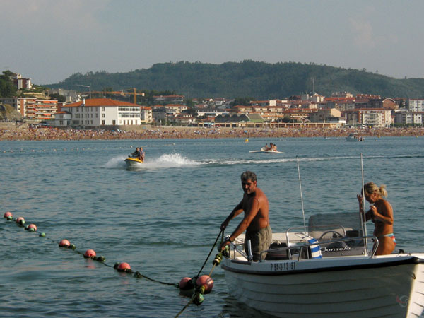 A boat, the sea, a beach and houses