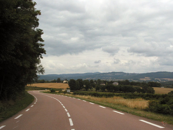 Bochtige weg, heuvels in de verte, bos