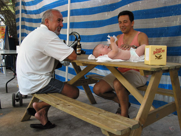 Baby op picknicktrafel, twee mannen erbij