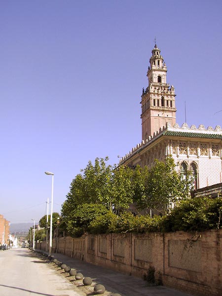 Achter een muur een Moors aandoend gebouw met toren die op een kleine Giralda lijkt