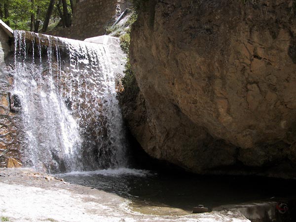 Kaarsrechte waterval tussen rode rotsen en naaldbomen