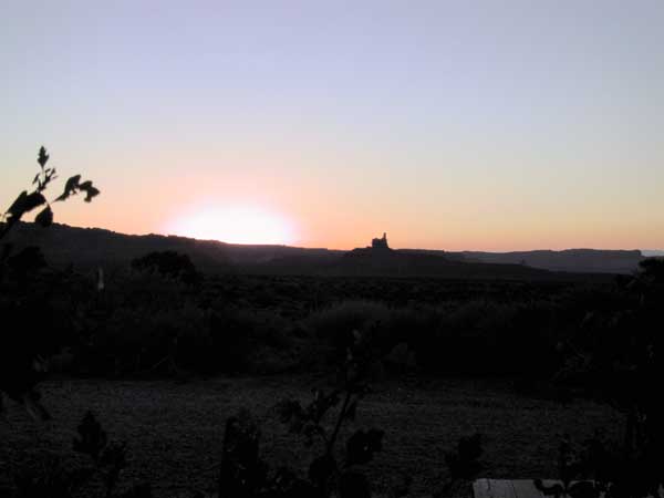 The sun rising, illuminating a single rock