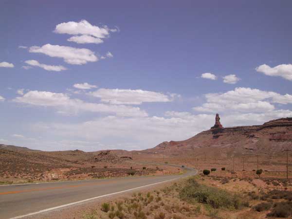 Asfaltweg door Monumentlandschap met rechts hoog hek