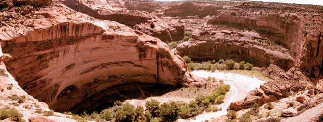 Miniature houses on a rim in the walls of a vast canyon