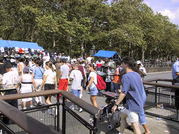 Mensen lopen over loopplank, marktkraam met petjes