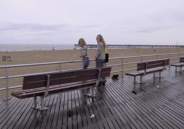 De kinderen vlak voor het strand, pier op de achtergrond