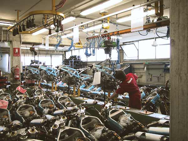 Rows of motorcycle frames, an employee in a red coverall