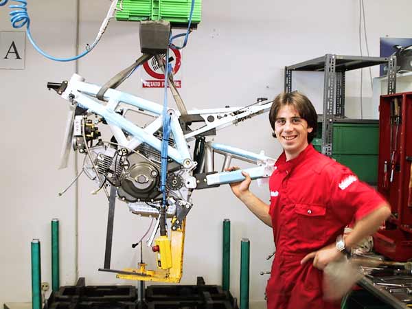 Proud man next to frame with motorcycle engine