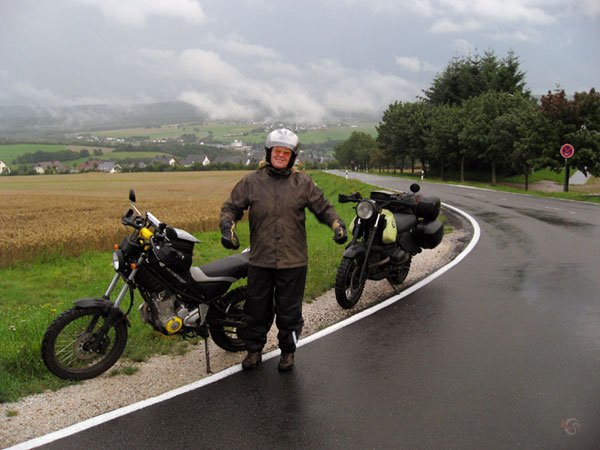 Sylvia in regenspullen bij de motoren