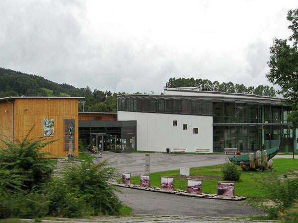 Laag gebouw van veel glas, kunstwerk in de vorm van enorme hand