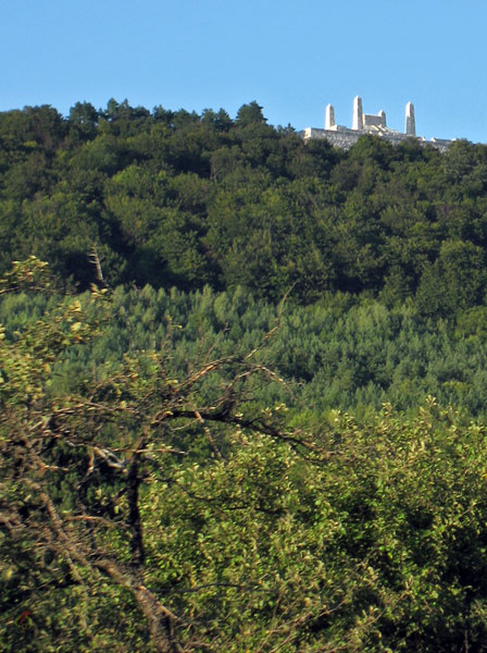 Vier witte obelisken boven de bomen uit