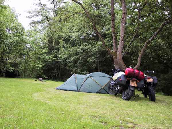 De twee motoren tegen een boom, naast de tent