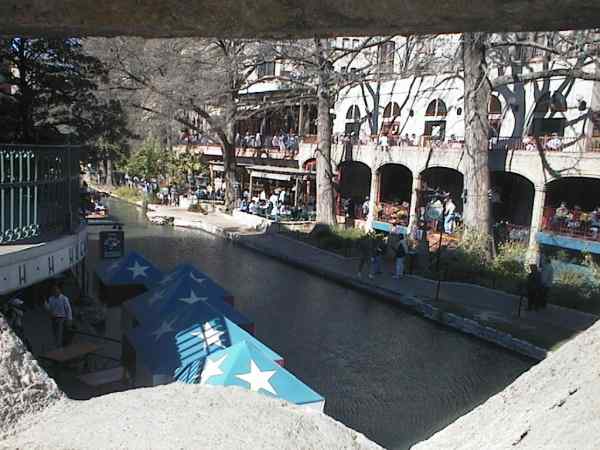 Water running through a town, trees and cafe's alongside