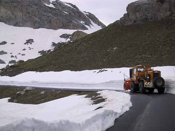 Sneeuwschuiver in een bocht, sneeuwwanden en kale rotsen