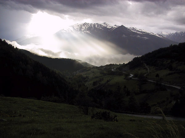 Zonnestralen door een gat in donkere wolken, schijnen op een donker berglandschap