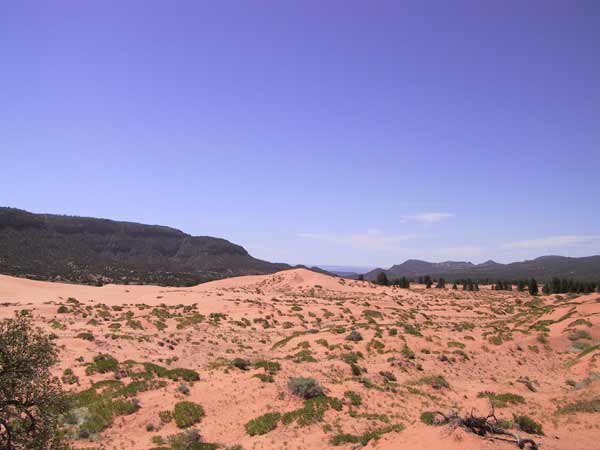 Duin van koraalroze zand, en verderop een opening tussen twee bergketens