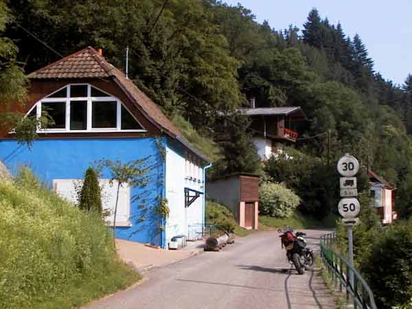Blauwgekleurd huis, motor ernaast geparkeerd